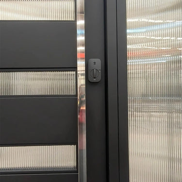 Modern pivot entry door combining large metal panels with narrow glass