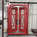 Red double arched entry doors with decorative cutout scrollwork and glass panels